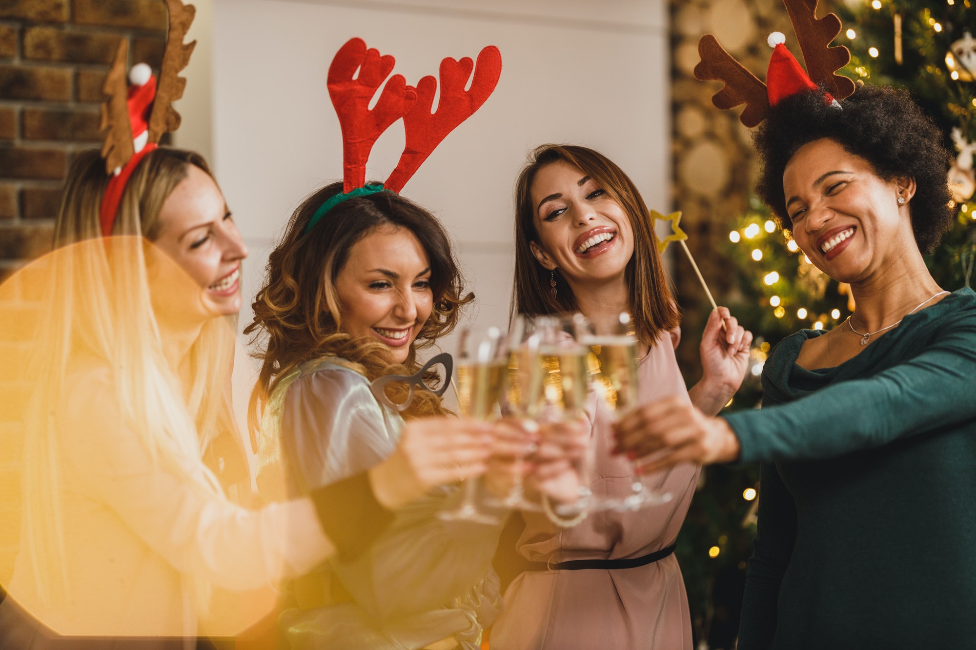 Four Multietnic Female Friends Make Toast As They Celebrate At Home Christmas Party